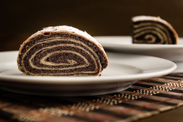 Foto strudel com sementes de papoula em uma placa de cerâmica branca com fundo de madeira