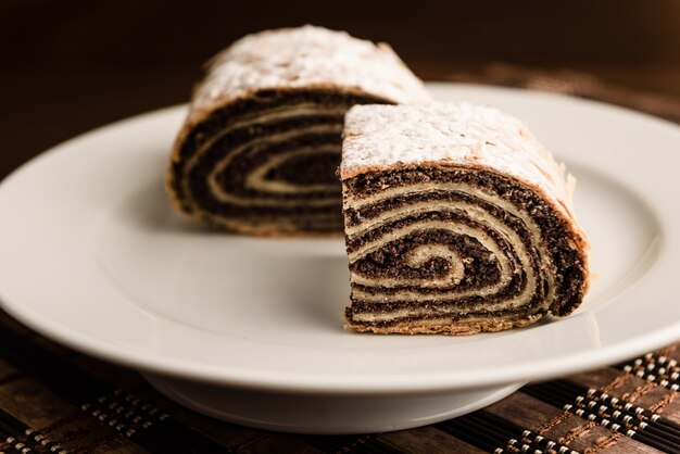 Strudel com sementes de papoula em uma placa de cerâmica branca com fundo de madeira