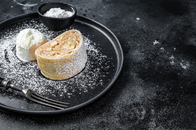 Strudel de maçã com canela, açúcar de confeiteiro e sorvete de baunilha em um prato