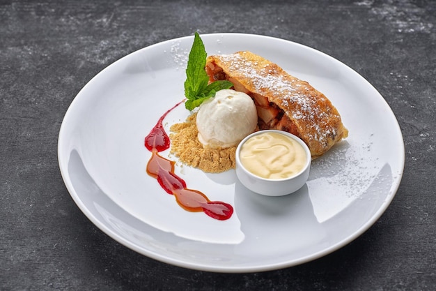 Strudel de sobremesa com maçãs e sorvete em um fundo escuro