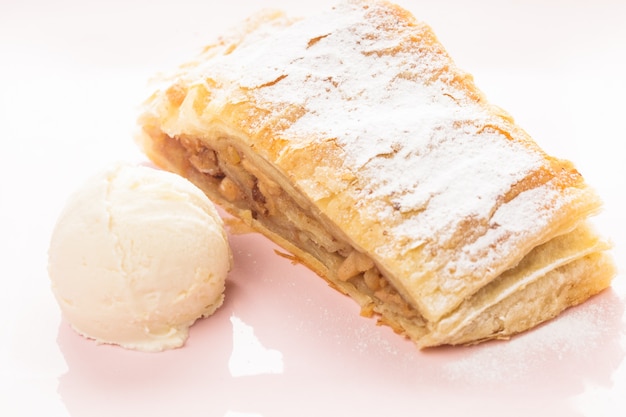 Strudel de manzana y bola de helado en una placa rosa