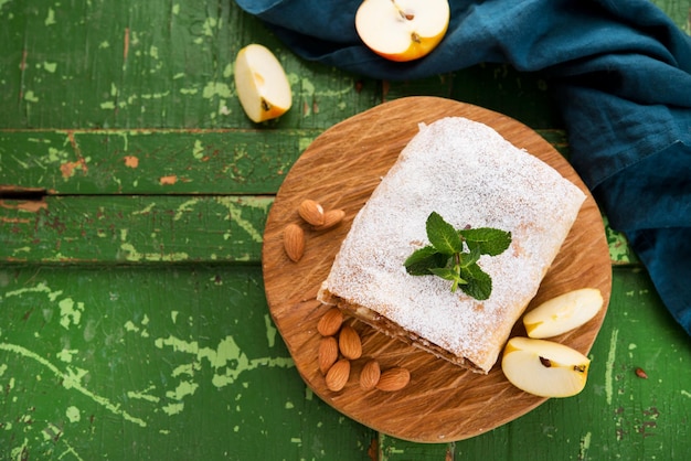 Strudel de manzana con nueces y pasas sobre una tabla de madera, vista superior