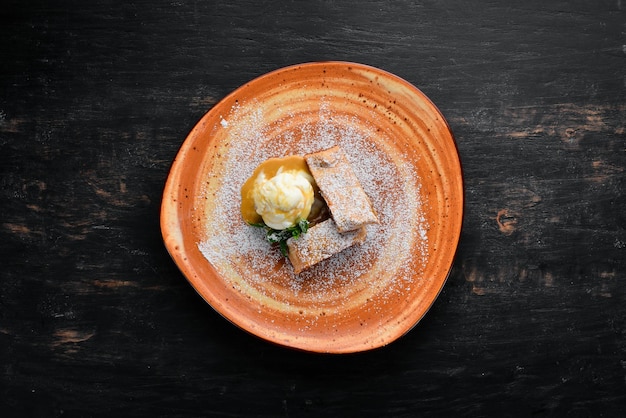 Strudel con manzanas y helado en un plato Postre Sobre un fondo de madera Espacio de copia libre Vista superior