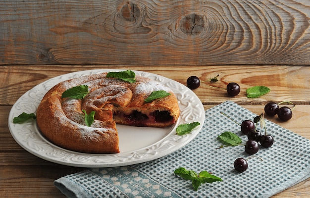 Strudel mit Kirschen auf Platte auf Holzoberfläche