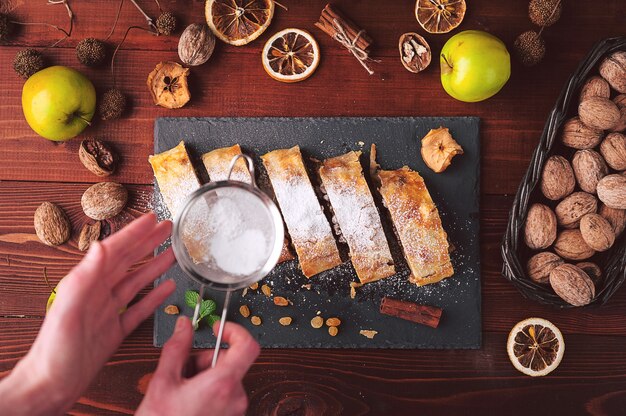 Strudel mit Äpfeln, Rosinen und Walnüssen im rustikalen Stil auf dunklem Hintergrund