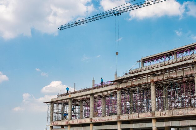 Struktur eines großen Gebäudes mit Arbeitskran und Gerüst auf der Baustelle an sonnigen Tagen