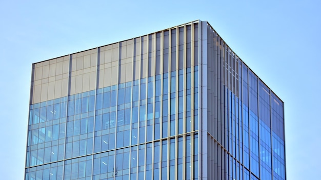 Strukturelle Glaswand, die den blauen Himmel reflektiert. Abstraktes modernes Architekturfragment