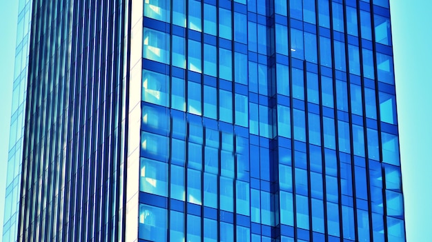 Strukturelle Glaswand, die den blauen Himmel reflektiert. Abstraktes modernes Architekturfragment