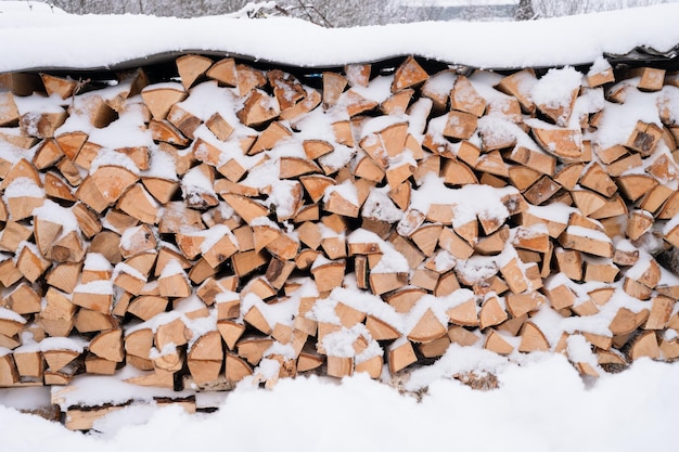 Foto strukturierter brennholzhintergrund gehacktes holz zum anzünden und heizen holzstapel mit gestapeltem brennholz birkenbaum bedeckt frischen eisigen gefrorenen schnee und schneeflocken kaltes wetter und schneereiche winterzeit