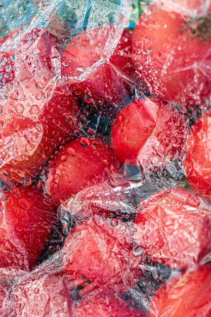 Strukturierter Hintergrund frisch gepflückter Tomaten unter Glas oder Folie mit Wassertropfen