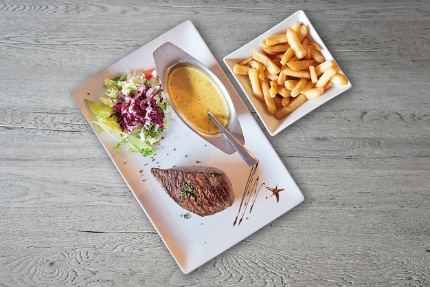 Strukturierter Holztisch und Platte mit gegrilltem Steak