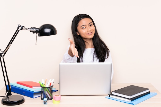 Student asiatisches Mädchen in einem Arbeitsplatz mit einem Laptop lokalisiert auf Beige