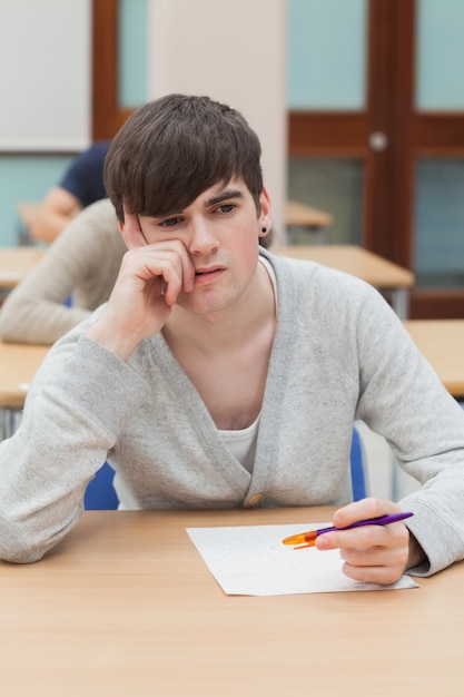 Student, der am Tisch denkt sitzt