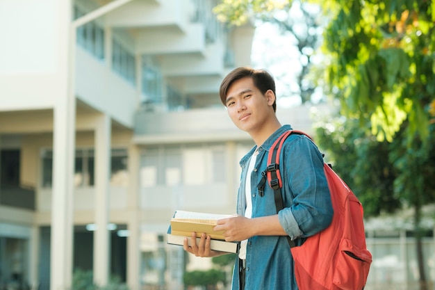 Student, der draußen steht und Bücher hält