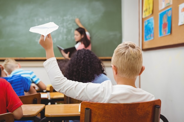 Student, der ein Papierflugzeug wirft