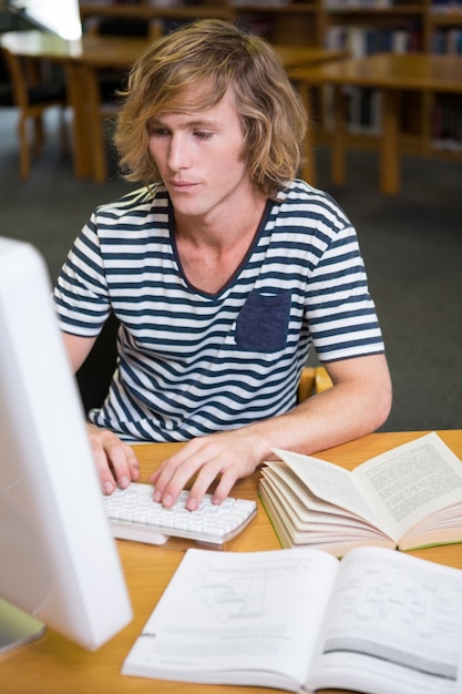 Foto student, der in der bibliothek mit computer studiert