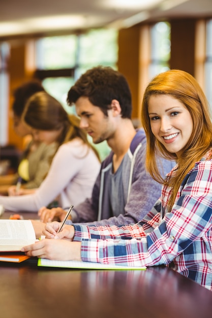 Student, der Kamera beim Studieren mit Klassenkameraden betrachtet