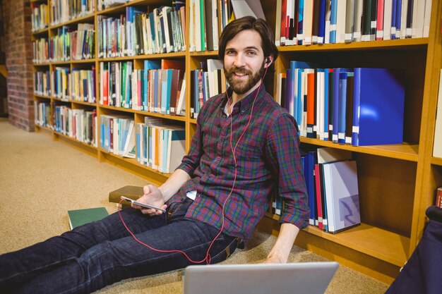 Student, der Telefon in der Bibliothek auf Boden verwendet