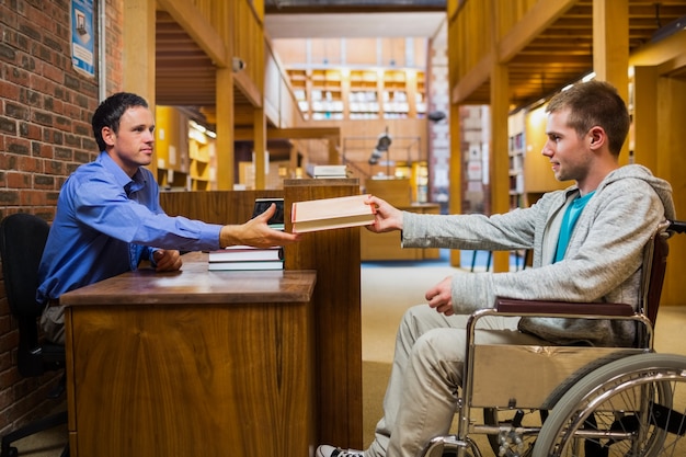 Student im Rollstuhl am Bibliotheksschalter