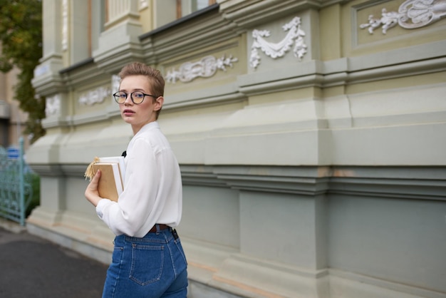 Student mit Brille, der mit einer Buchkommunikation durch die Stadt geht