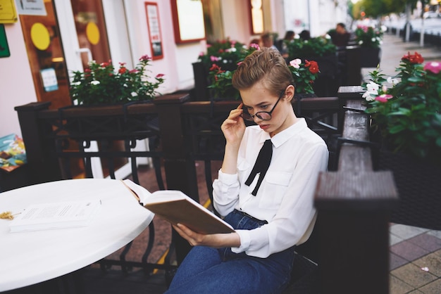 Student mit einem Buch in den Händen im Freien in einem Sommercafé Restkommunikation