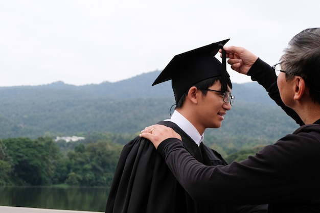 Student mit Glückwünschen, Absolventen, die ein Abschlusskleid der Universität tragen.