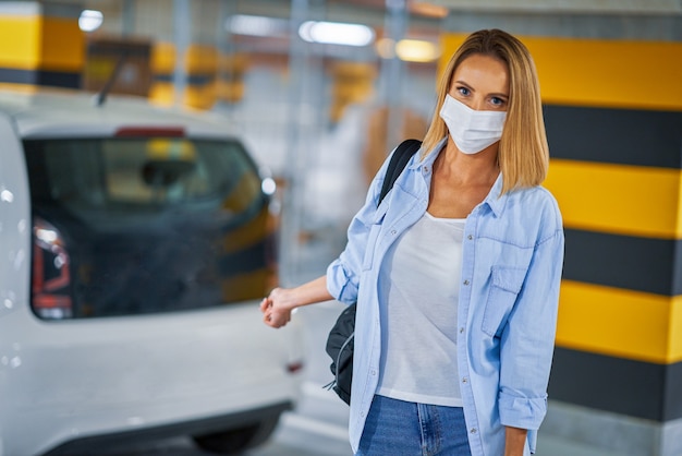 Student mit Maske, der das Auto in der Tiefgarage verlässt