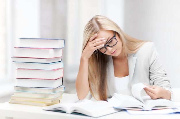 Student mit Stapel Büchern und Notizen, die drinnen lernen