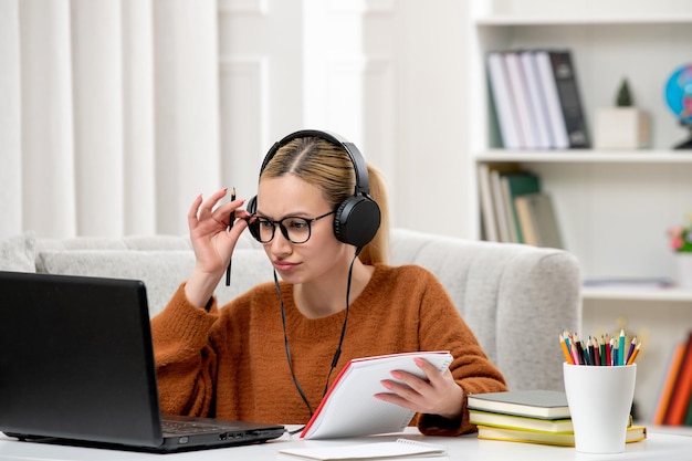 Student online süßes Mädchen in Brille und Pullover, das am Computer studiert und eine Brille berührt