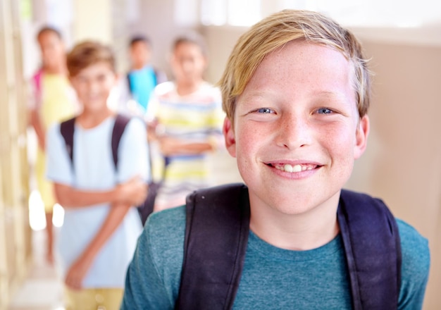 Foto student porträt und kind mit lächeln im flur mit bildungsstudium und rucksack für die rückkehr zur schule junge junge und lernt mit selbstvertrauen auf dem campus mit kindern und glücklich aus dem unterricht