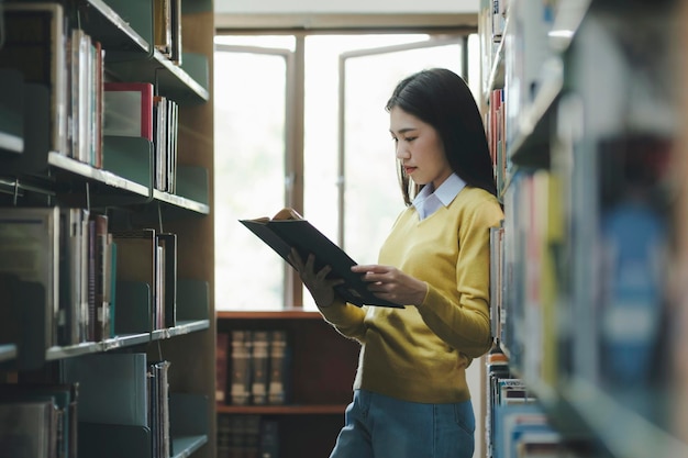 Student steht und liest Buch in der Bibliothek