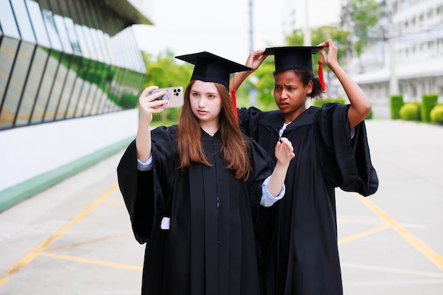 Student trägt Kleid und macht Foto per Smartphone-Abschluss Glücklicher Absolventenerfolg und Feier Herzlichen Glückwunsch