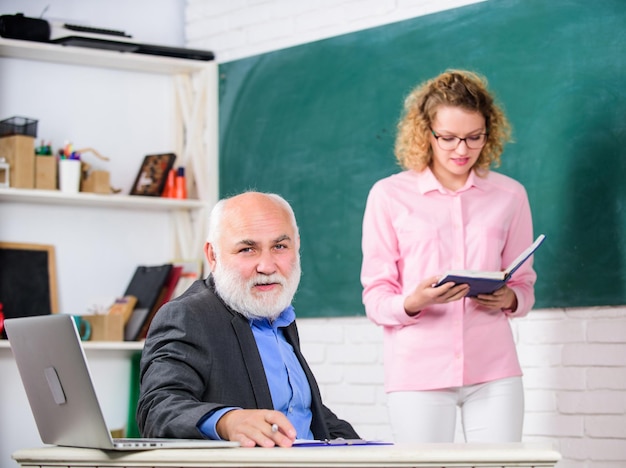 Student und Tutor mit Laptop bestehen Prüfung Lehrerzimmer Studentin mit Tutor Mann an der Tafel Studentin liest eine Präsentation Oberlehrer und Frau in der Schulstunde Schlechte Note