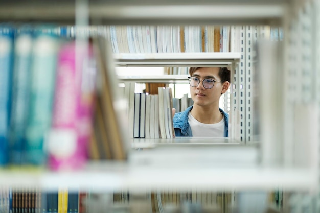 Student wählt und liest Buch in der Bibliothek