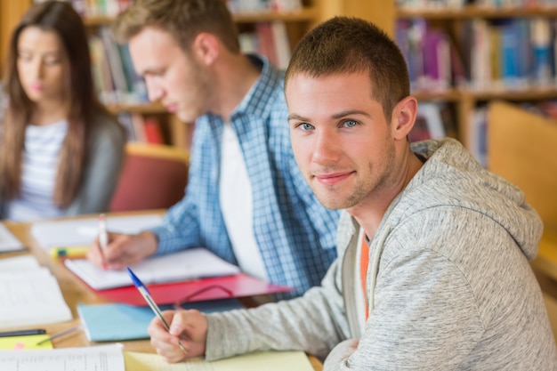 Studenten, die Anmerkungen am Bibliotheksschreibtisch schreiben