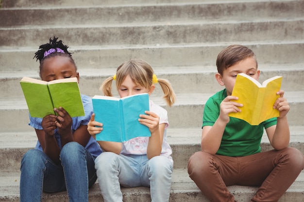 Foto studenten, die auf schritten sitzen und bücher lesen