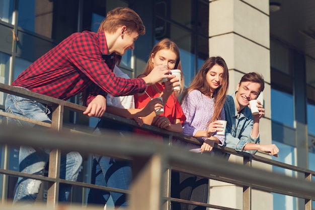 Studenten genießen eine Tasse Kaffee, um auf die Straße zu gehen. Junge Leute morgens im Freien mit einer Tasse Energy-Drink