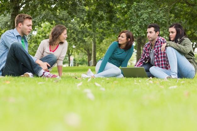 Studenten mit dem Laptop, der im Park sitzt