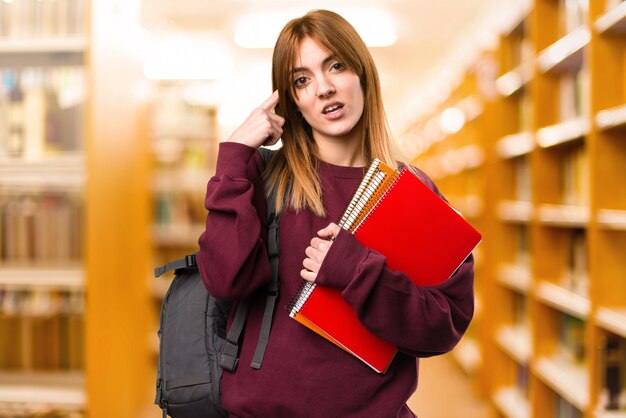 Studentenfrau, die verrückte Geste auf unfocused Hintergrund macht. zurück zur Schule