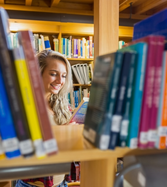 Studentenlesebuch unter Bücherregalen in der Bibliothek