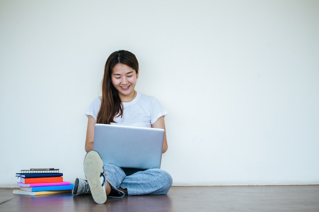 Studentenmädchen, das Bericht mit Laptop macht und in der Schule sitzt.