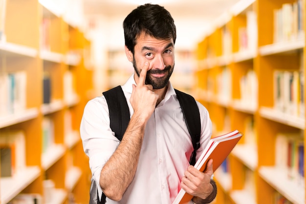 Studentenmann, der etwas auf defocused Bibliothek zeigt