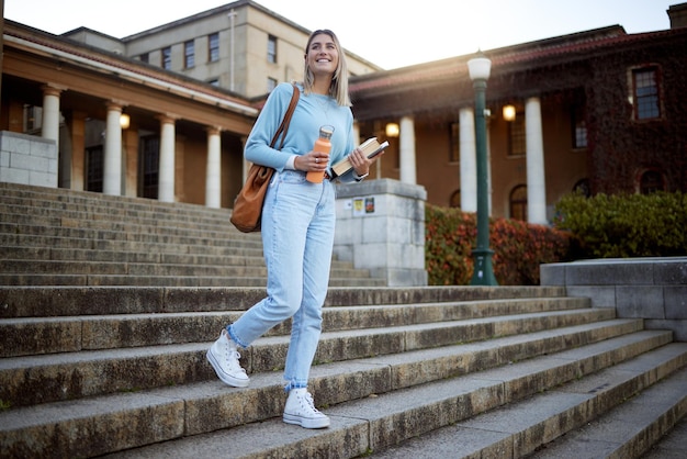 Studentin auf Campustreppen und Universitätsausbildung mit Lern- und akademischen Zielen mit Stipendium im Freien Bücher zum Lesen von Studien und glücklichen Menschen mit erfolgreichem College-Leben und Studium