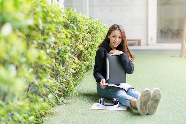 Studentin, die auf Rasenbank am Campus sitzt