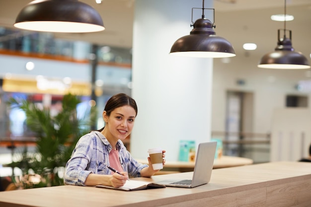 Studentin, die im Café an einem Projekt arbeitet