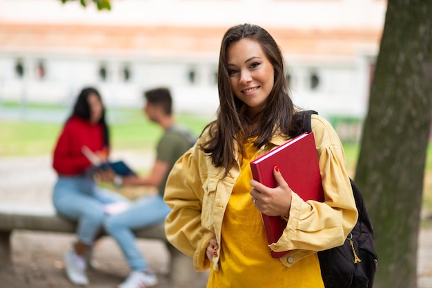 Studentin hält ein Buch vor einer Gruppe von Freunden