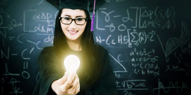 Studentin im Aufbaustudium, die eine Glühbirne im Unterricht hält