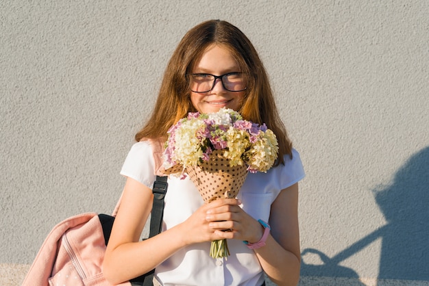 Studentin in Gläsern mit Rucksack und Blumenstrauß