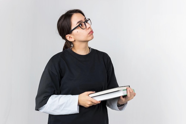 Studentin mit Brille schaut nachdenklich zur Seite. Sie hält Bücher zum Lesen von Studium oder Bildung