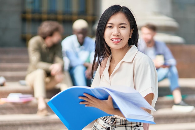 Studentin mit Exposé vor dem Universitätsgebäude